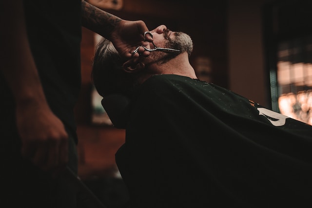 A man getting his beard trimmed at his local barber shop